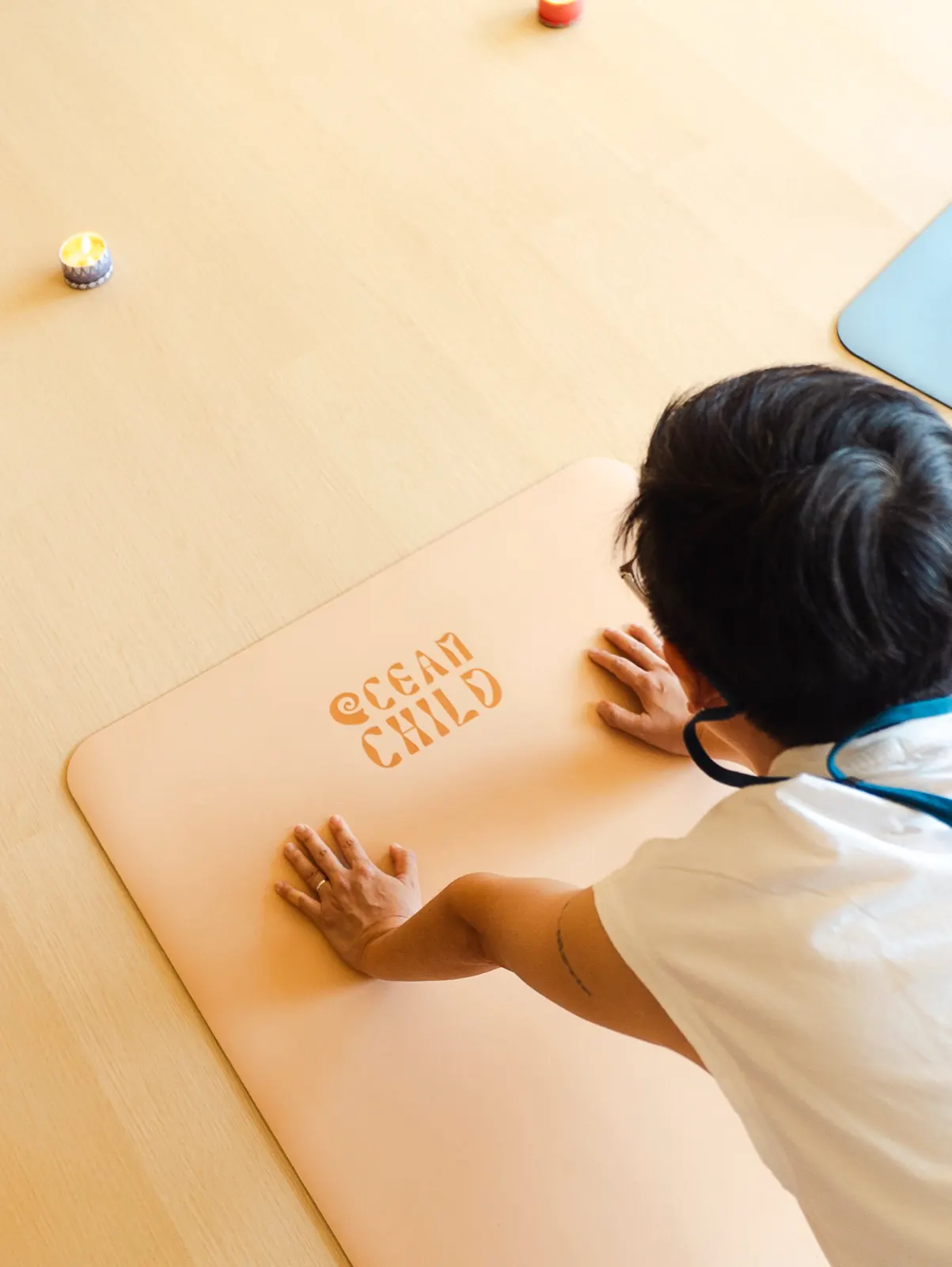 Grounded downward-facing dog on custom Oceanchild studio mat with candlelight
